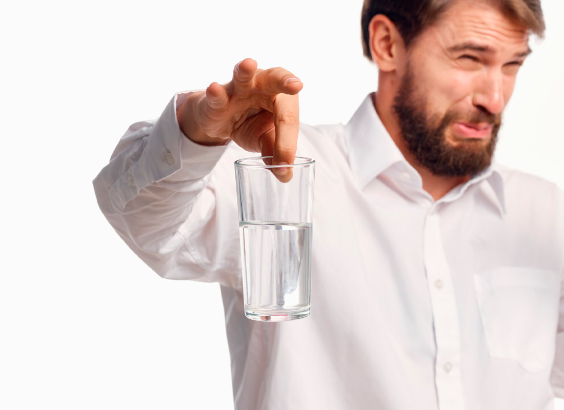 Hombre con vaso de agua y cara de asco