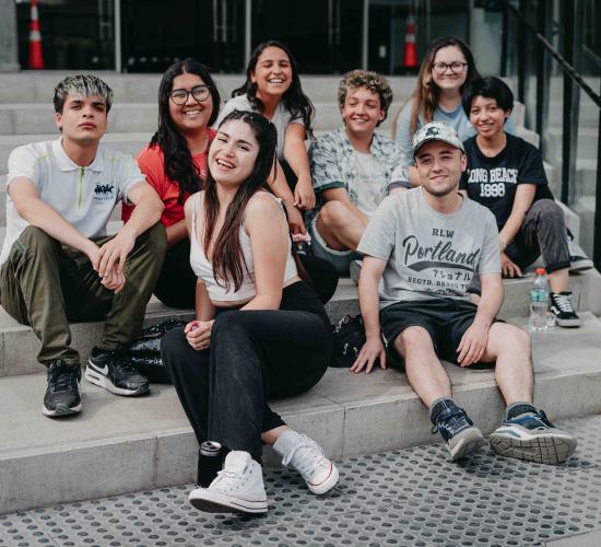 Ocho estudiantes sentadas y sentados en el frontis de la Facultad de Administración y Economía.