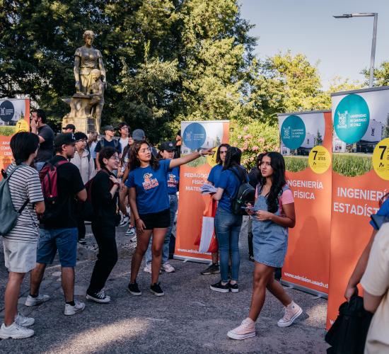 Grupo de estudiantes en el campus, se ve como ven el campus y una recibe indicaciones