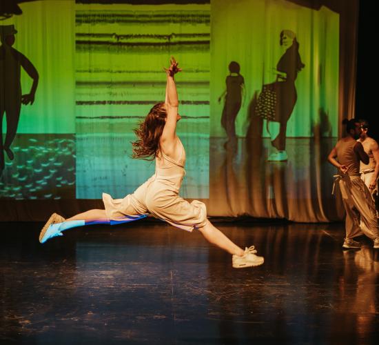 Grupo de personas bailando, donde se logra apreciar a una dando un salto con las piernas extendidas 