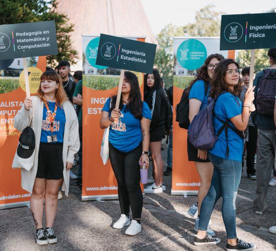 Estudiantes con letreros para que los nuevos puedan guiarse 