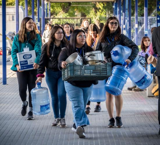 Voluntariado cargando bidones de agua y ollas