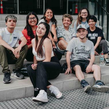 Ocho estudiantes sentadas y sentados en el frontis de la Facultad de Administración y Economía.