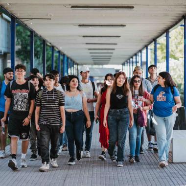 Conglomerado de estudiantes caminando por uno de los pasillos cercano a la Casa Central. En esta ocasión se encuentra una guía mostrándoles la Universidad.