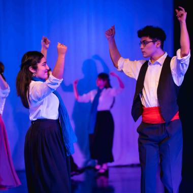 Pareja de estudiantes bailan música folclórica en una presentación.