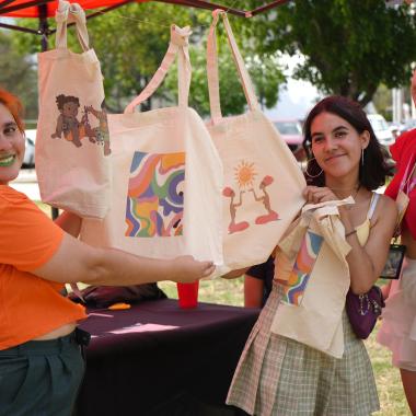 Estudiantes en un stand mostrando bolsas de tela