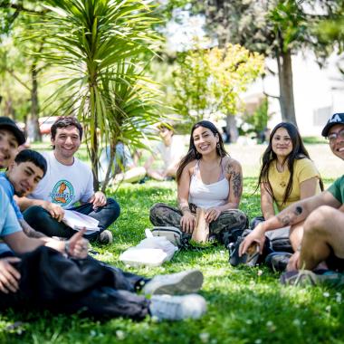 Estudiantes sentados en el pasto