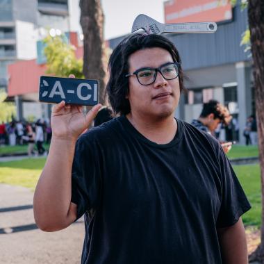 Foto de un estudiante con una llave inglesa en la cabeza