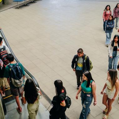 Alumnos subiendo por una escalera mecánica del edificio nuevo de la Facultad de Administración y Economía