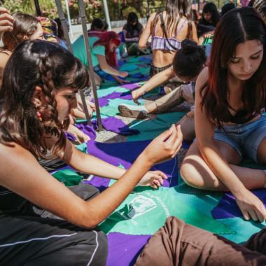 se muestra un grupo de mujeres en el campus preparándo las actividades a realizar en distintos sectores del Campus Universitario