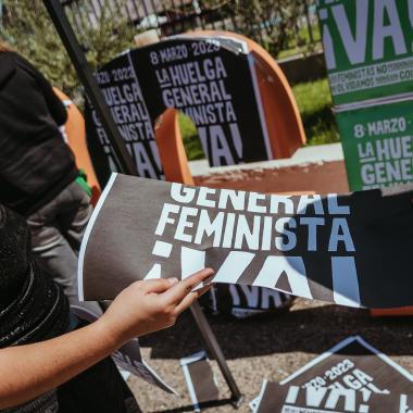 Esta imagen muestra como pegan afiches sobre la huelga del ocho de marzo