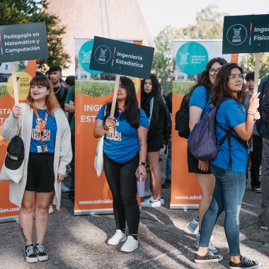 Estudiantes con letreros para que los nuevos puedan guiarse 