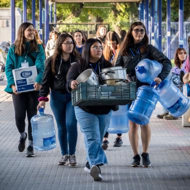 Voluntariado cargando bidones de agua y ollas