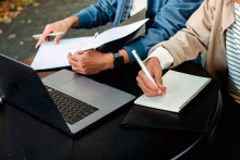 Personas con lápiz en las manos y papel al frente de un notebook 