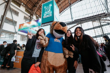 Estudiantes asistentes a feria SIAD junto a corpóreo de la Universidad