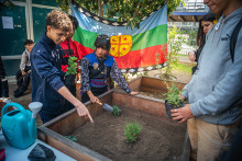 lawentuchefe Selene Railaf entrega conocimientos ancestrales a estudiantes. Bandera mapuche de fondo.