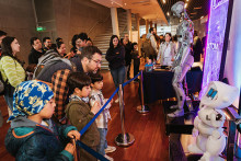 Familia visita santa Usach en Neurofest. En el fondo se divisa al robot ATOM