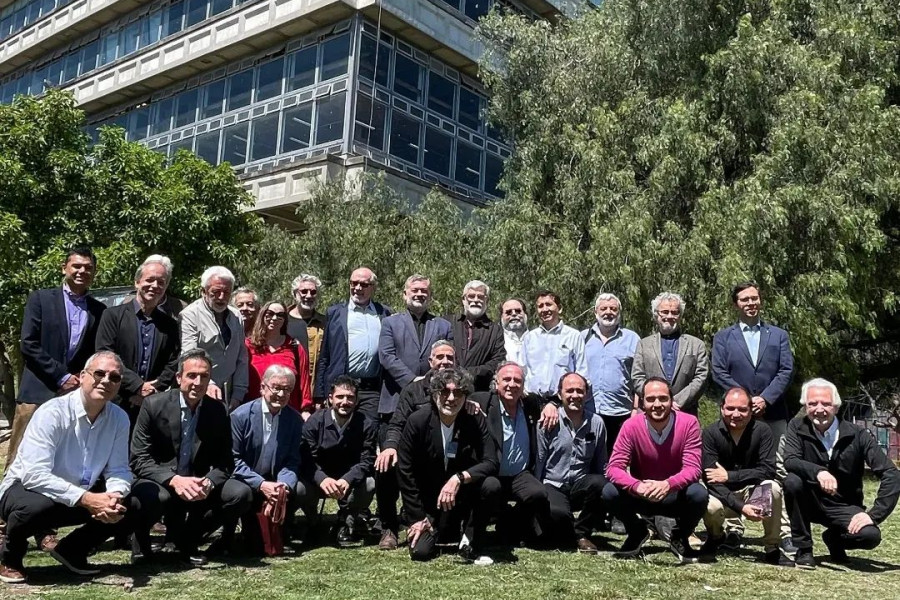 Académicos de la Facultad de Arquitectura Usach en encuentro internacional en Argentina. Posan sobre un verde pasto y un edificio de la Universidad.