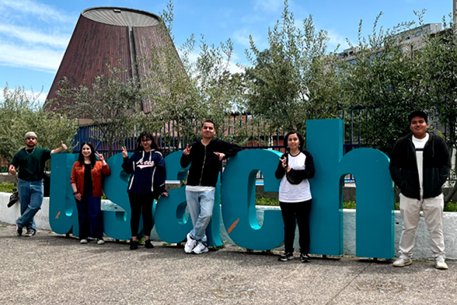 Estudiantes posan en letras Usach . Detrás se aprecia el edificio Planetario