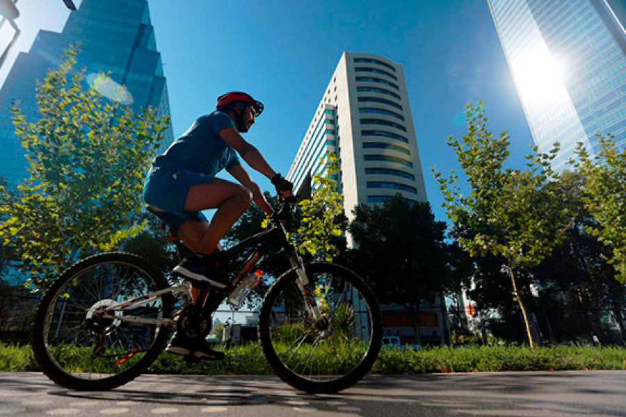 Ciclista pasando por al frente de unos edificios 