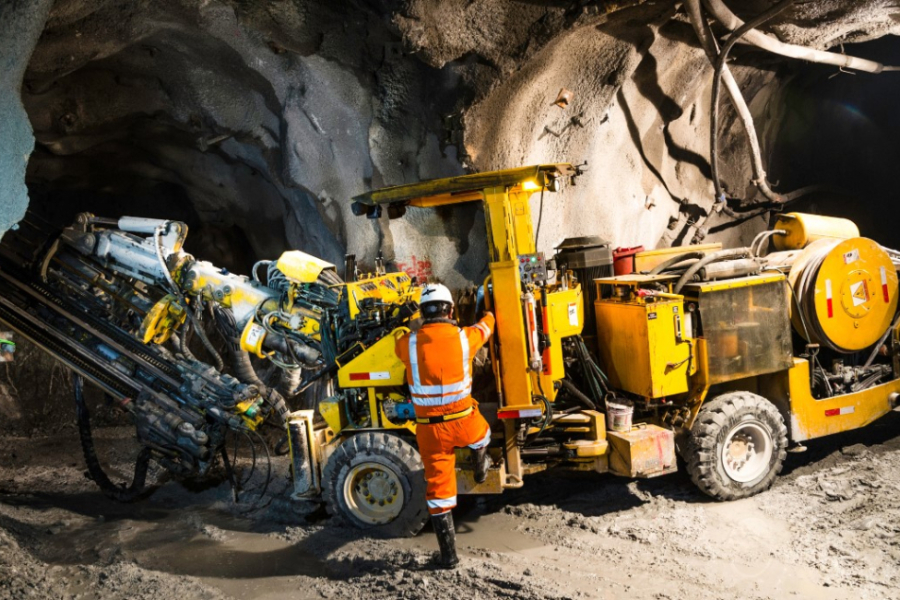 Minero trabajando en la mina con máquina extractoras de cobre.