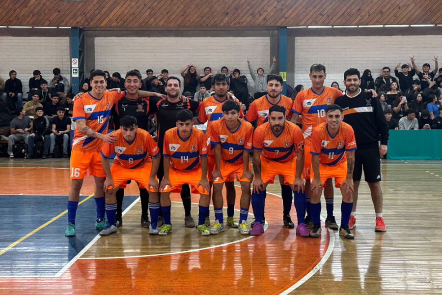 Jóvenes deportistas con vestimentas de la selección Usach, en donde predomina en color naranjo con algunas líneas azules sobre el pecho. Los estudiantes se encuentran posando a la foto en el gimnasio de al universidad.