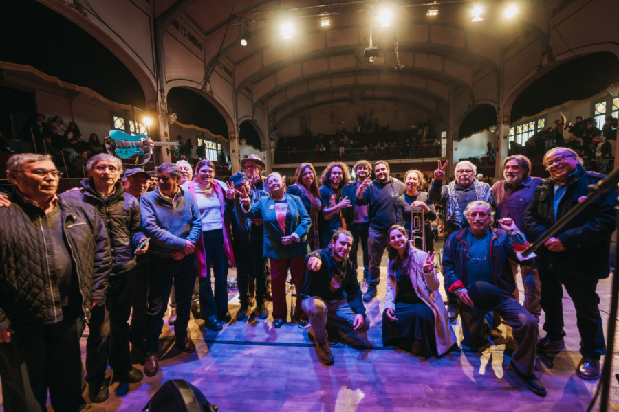Integrantes de la Corporación Solidaria UTE-USACH, la presidenta de la Federación de Estudiantes Usach, parte de la comunidad universitaria y los músicos de Sol y Lluvia, posan en el escenario del Teatro Aula Magna