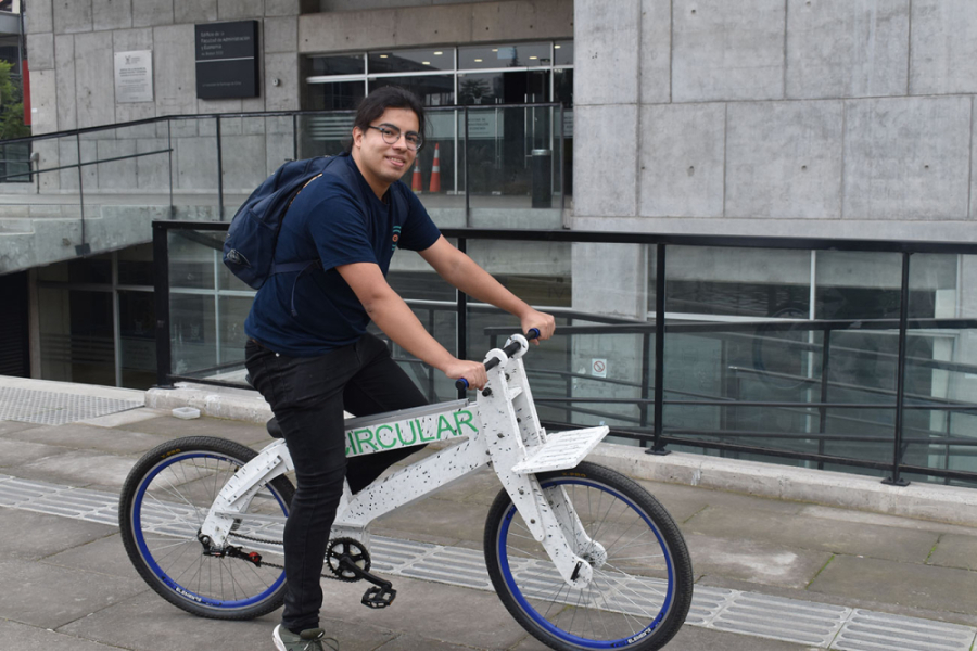 Estudiante sobre la bicicleta en el frontis del edificio FAE