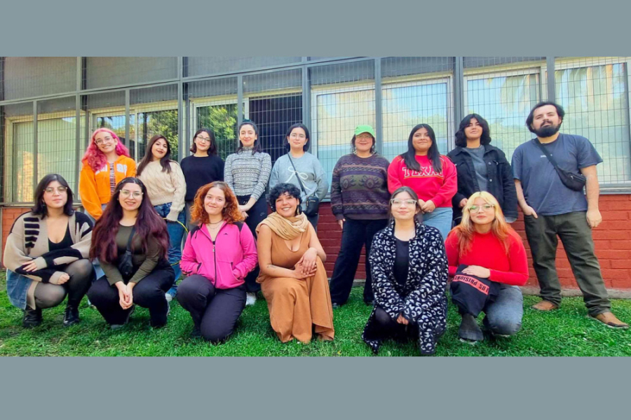 Estudiantes de la actividad posan a la cámara en el sector de las salas de clases del Departamento de Historia. en la imagen aparece 15 estudiantes mujeres y un profesor.
