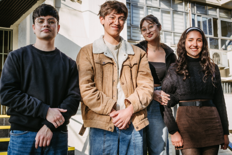 En la fotografía aparecen los estudiantes ganadores del concurso. Dos hombres y dos mujeres que posan sobre una escalera de entrada al edificio de comunicaciones Usach
