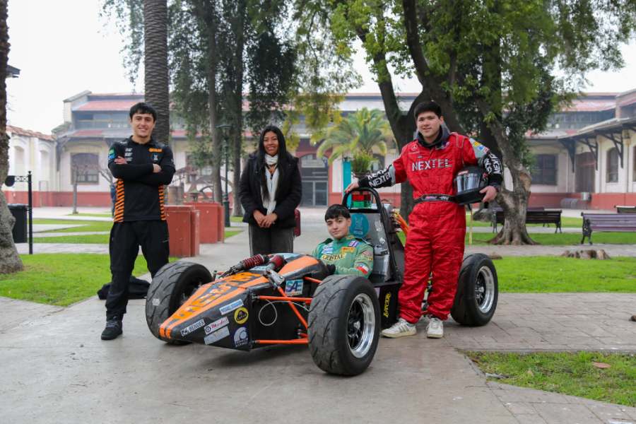 En la fotografía se puede apreciar al Equipo Esus Usach. En el centro aparece el automóvil de carrera elaborado por equipo. De fondo, la Escuela de Artes y Oficios.