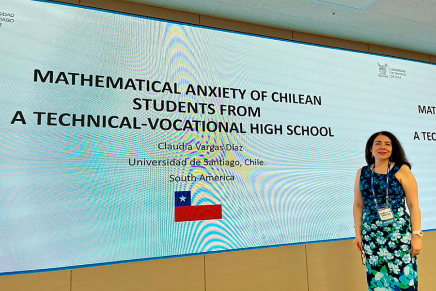 Dra. Vargas aparece de pie frente a la ppt de una presentación e su autoría. 