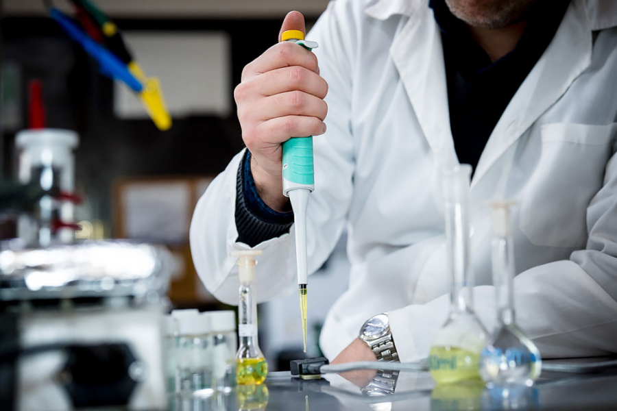 Investigador con delantal blanco trabaja en su puesto de trabajo en el laboratorio