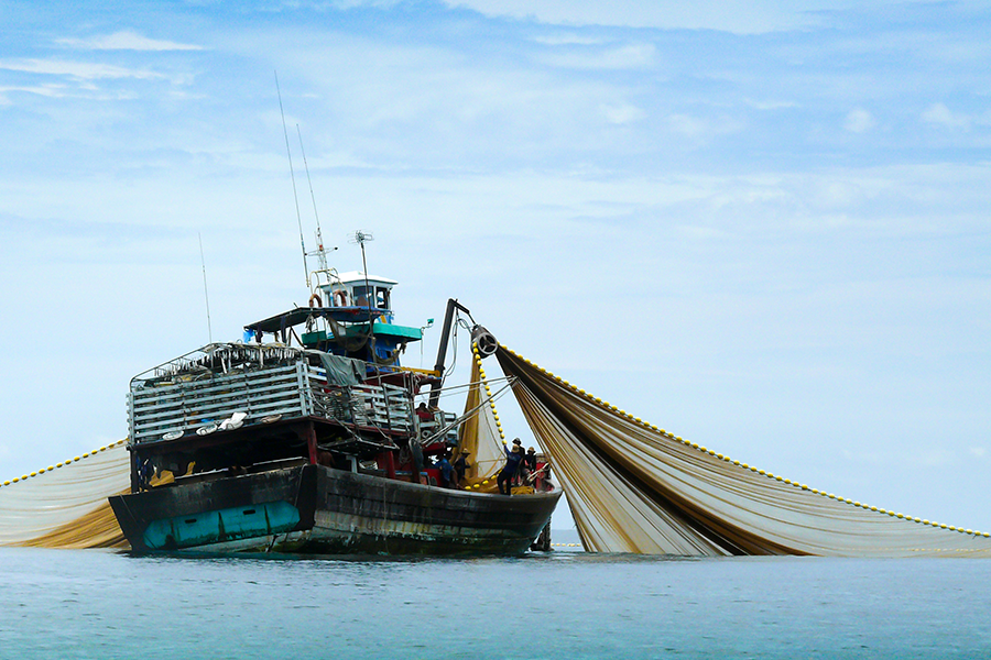 Imagen de un gran barco pesquero con una red desplegada a ambos lados.