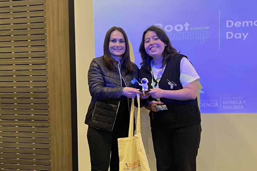En la fotografía aparecen dos mujeres, una estudiante y una académica, en el momento de la premiación del evento