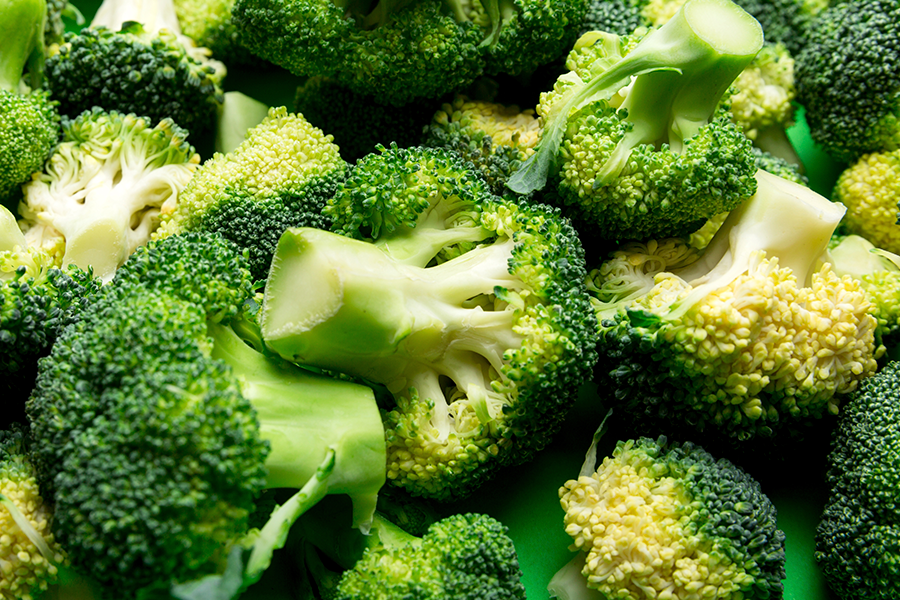 Close-up detalhado de floretes de brócolis frescos e de cor verde intensa, em que se apreciam a textura e as variações de cor do vegetal.