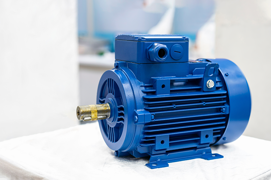 Close-up de um motor elétrico industrial azul sobre uma superfície branca em um ambiente interno bem iluminado.