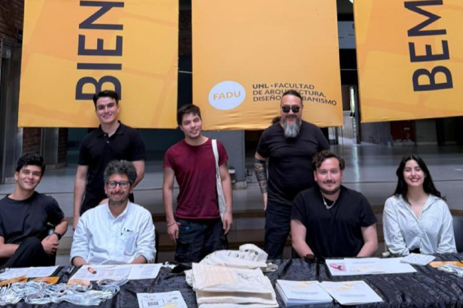 En la imagen aparecen académicos y estudiantes de la facultad que participaron del Congreso. De fondo tres pendones colgantes de color naranjo y letras negras