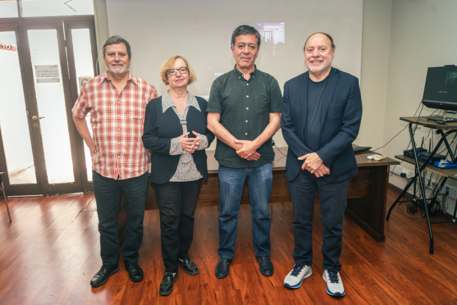 Cuatro personas de pie miran a la cámara, de izquierda a derecha: un hombre, una mujer y dos hombres