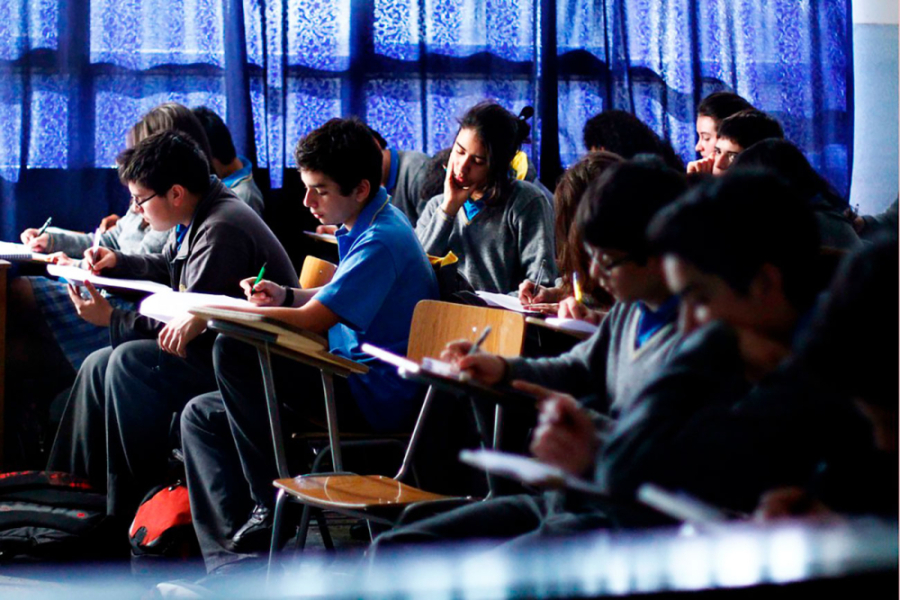 En la imagen aparecen jóvenes estudiantes dando la prueba Paes en una sala de clases