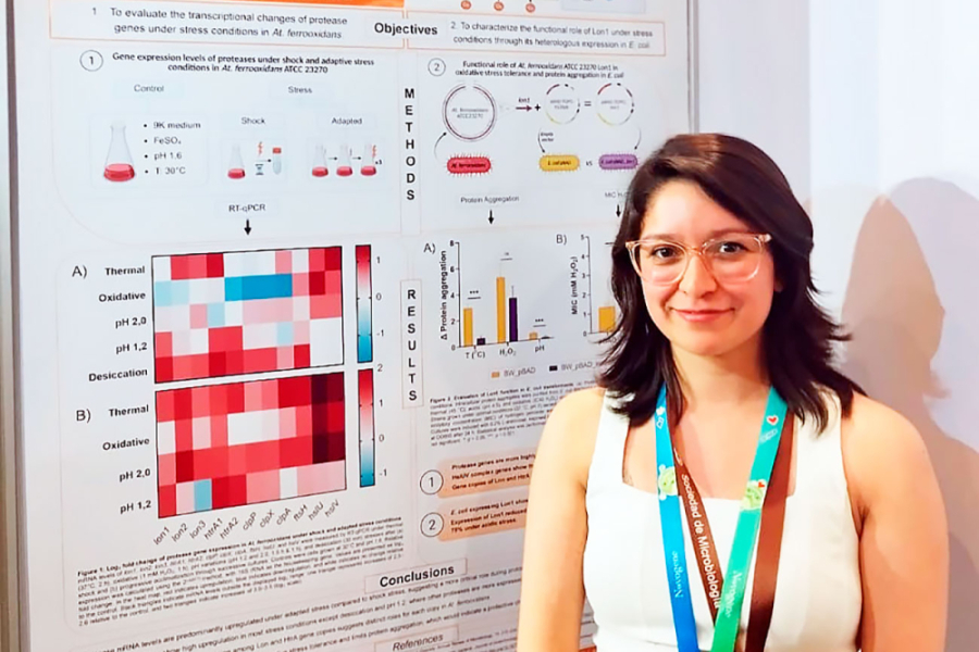 En la fotografía aparece la estudiante de doctorado Javiera Acevedo, junto a un poster científico.