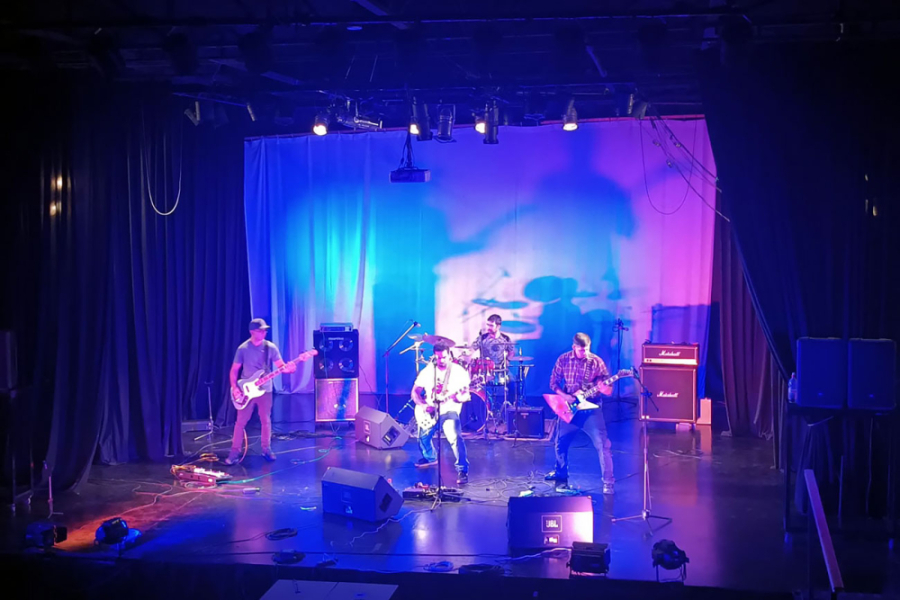 En la imagen se muestra una banda de cuatro hombres tocando en la sala de artes Victor Jara