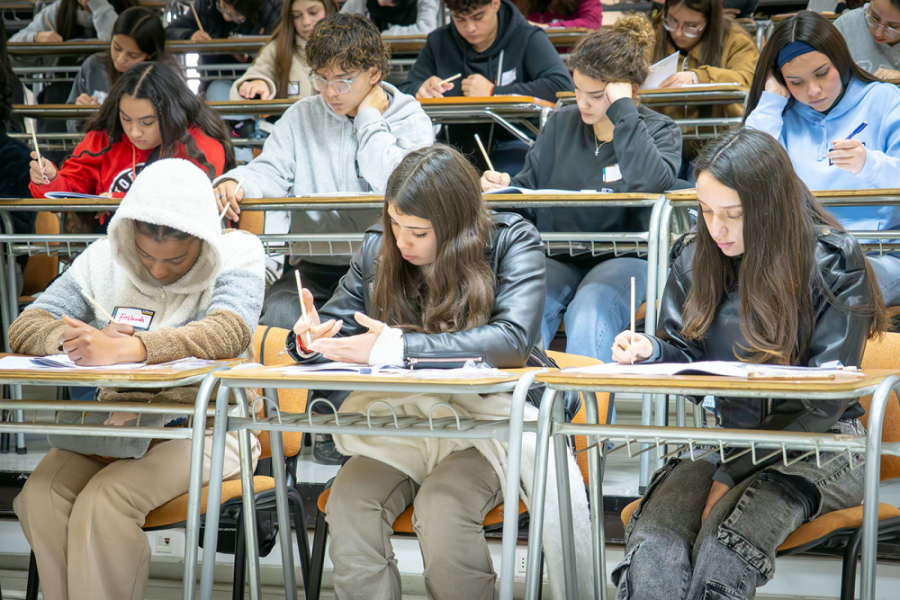 La imagen muestra a estudiantes, sentados en sus pupitres rindiendo la prueba ensayo