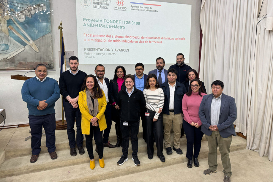 En la imagen aparecen profesores y estudiantes del magister en el Salón de Honor Usach. De fondo, la portada de un ppt de presentación.