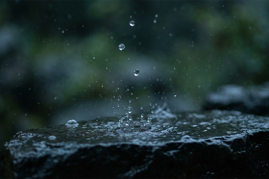 Gotas de agua que salpican una piedra oscura y húmeda durante una lluvia.