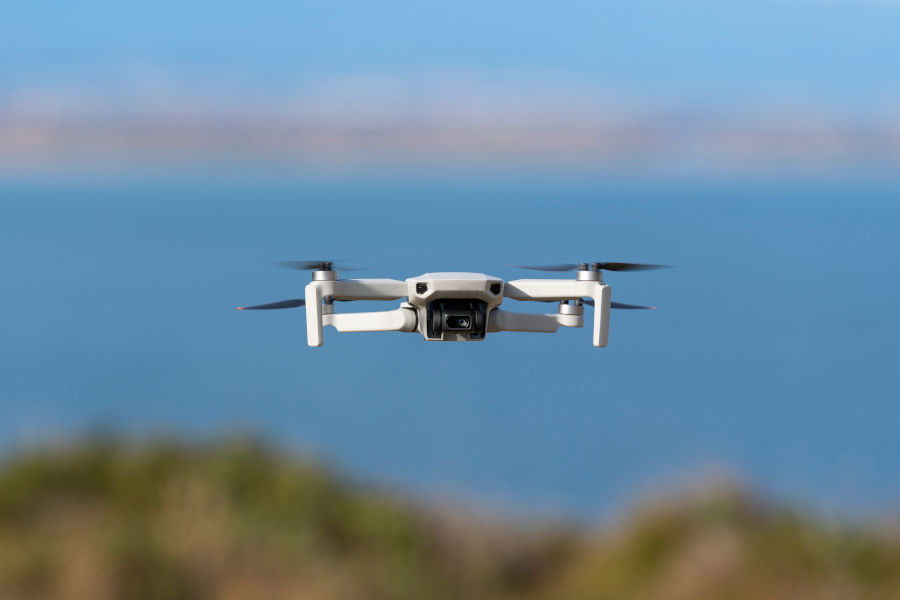 Un dron blanco sobrevolando un océano azul.