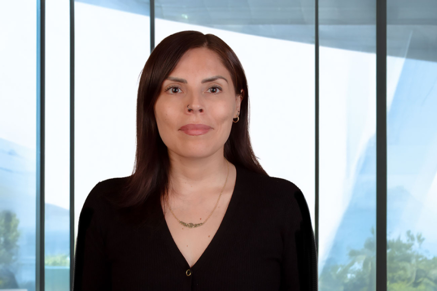 En la fotografía aparece la Dra. Fabiola Miranda, académica del Departamento de Gestión y Políticas Públicas. Viste camisa negra y de fondo aparecen unos ventanales correspondiente al edificio FAE