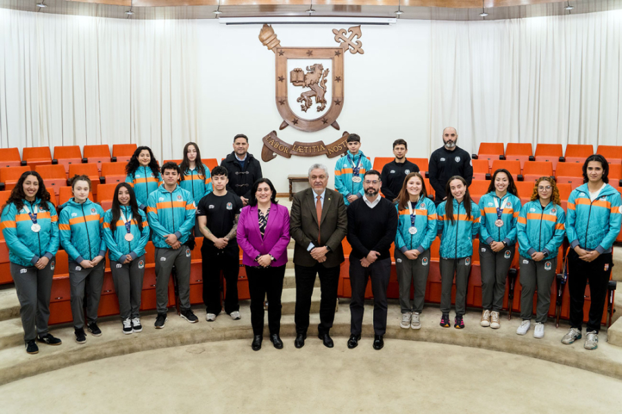 La foto muestra a la delegación deportiva y a los entrenadores en el Salón de Honor. Al centro el rector Palominos, a la derecha la vicerrectora y a la izquierda el jefe del departamento de deportes