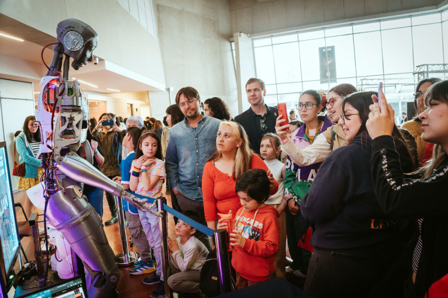 La imagen muestra al público asistente al evento observando un robot
