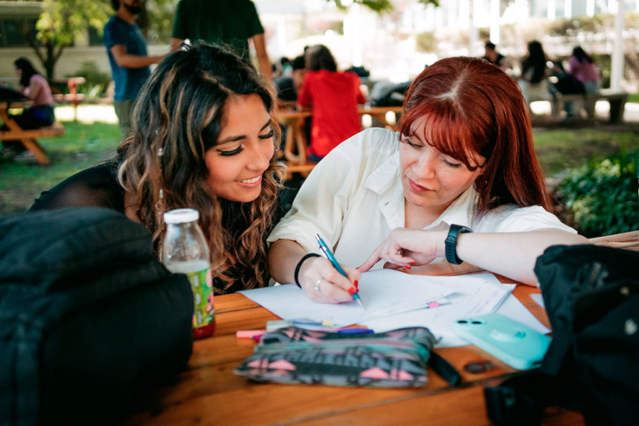 En la imagen aparecen dos jóvenes estudiando en los patios de la universidad